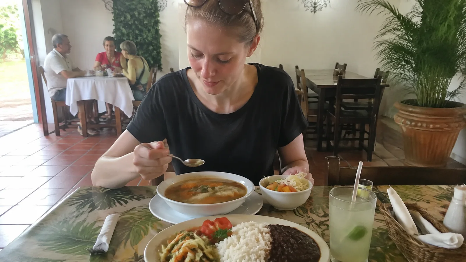 Woman eating a bowl of soup at a casual restaurant table.