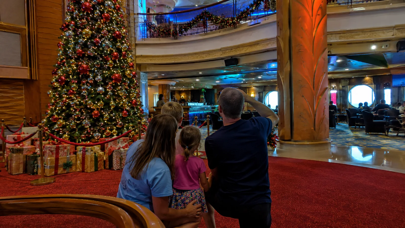 Family looking at a large decorated Christmas tree inside a cruise ship atrium