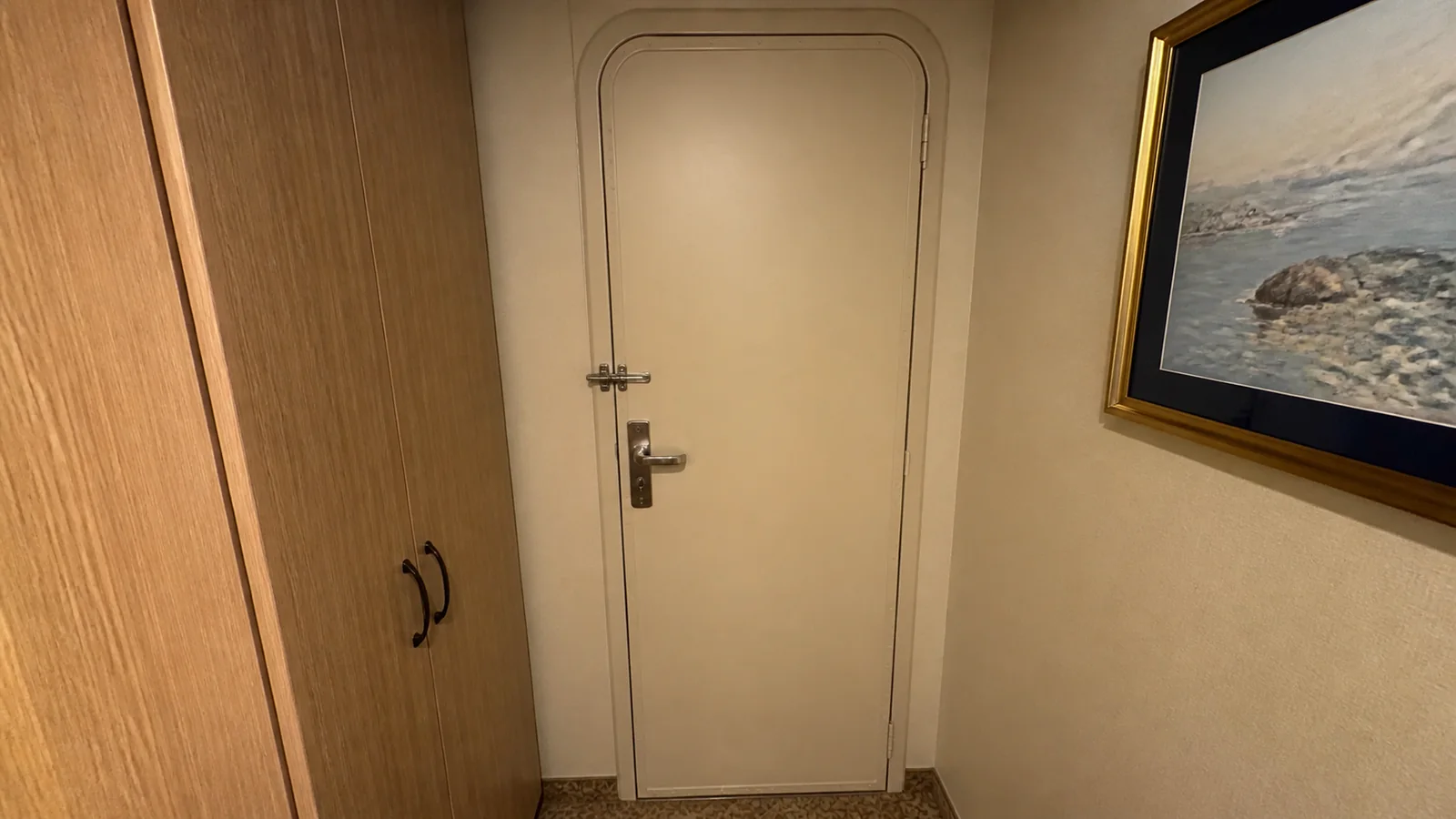Closed connecting door stands beside a wardrobe and framed picture.