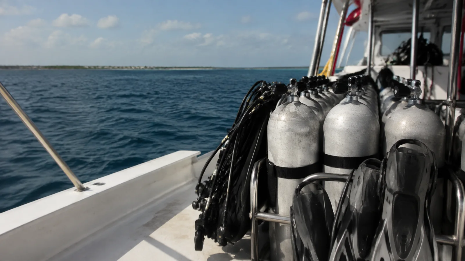 Rows of scuba tanks secured beside the railing of a boat.