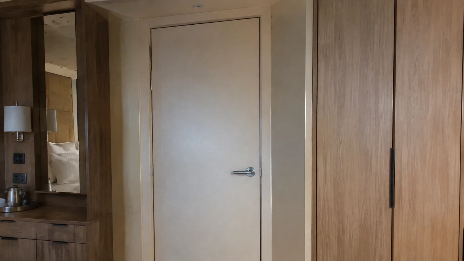 Closed interior door beside a wooden wardrobe in a ship cabin.
