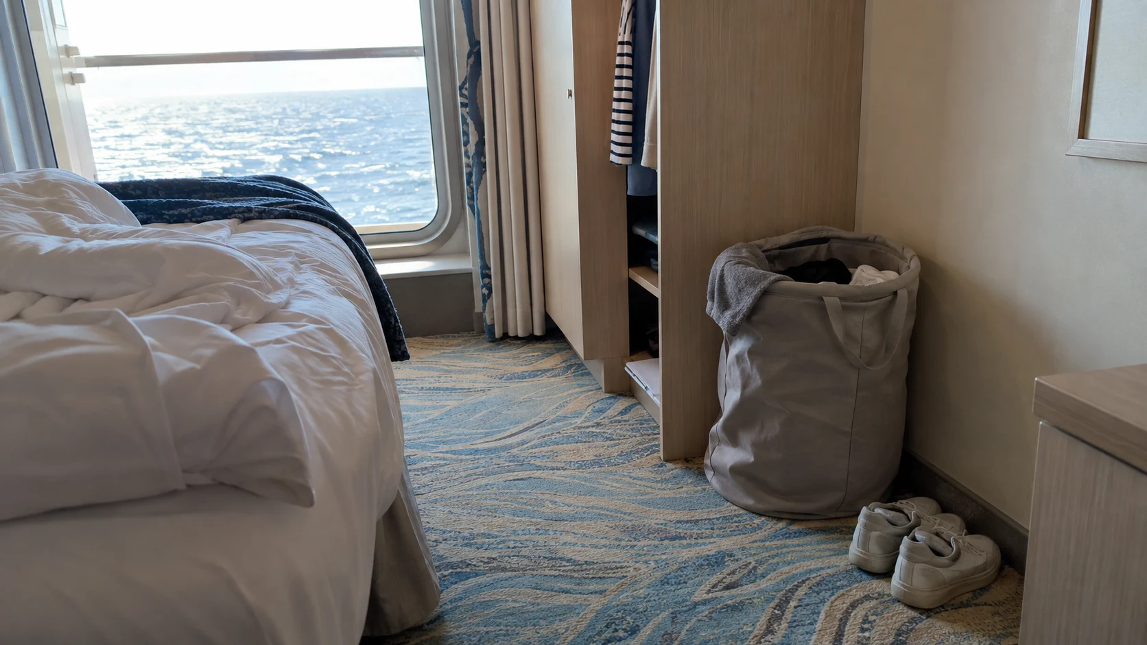 Fold-flat laundry bag tucked beside a cruise cabin wardrobe.