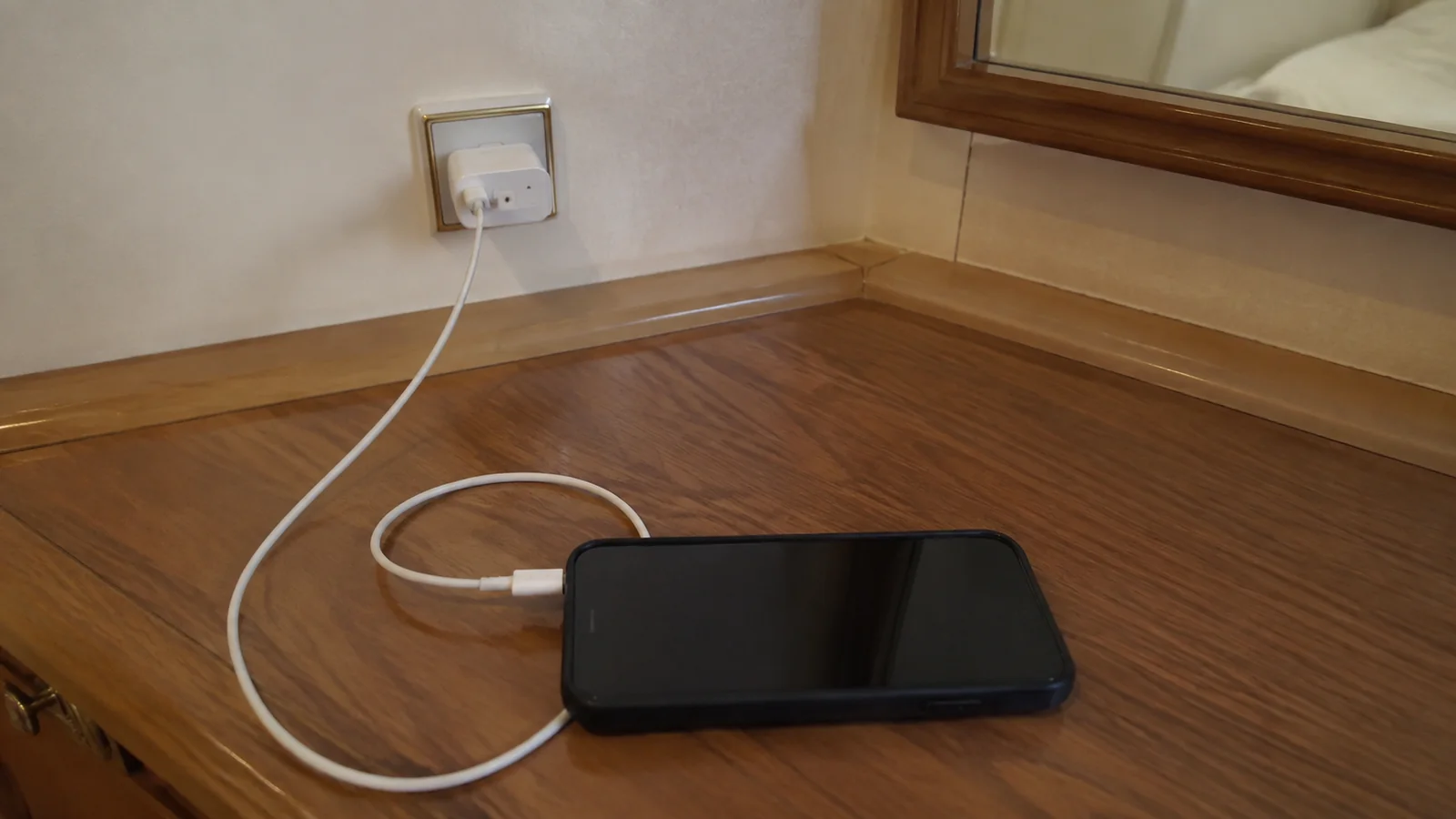 Tablet charges from a wall outlet on a wooden desk.
