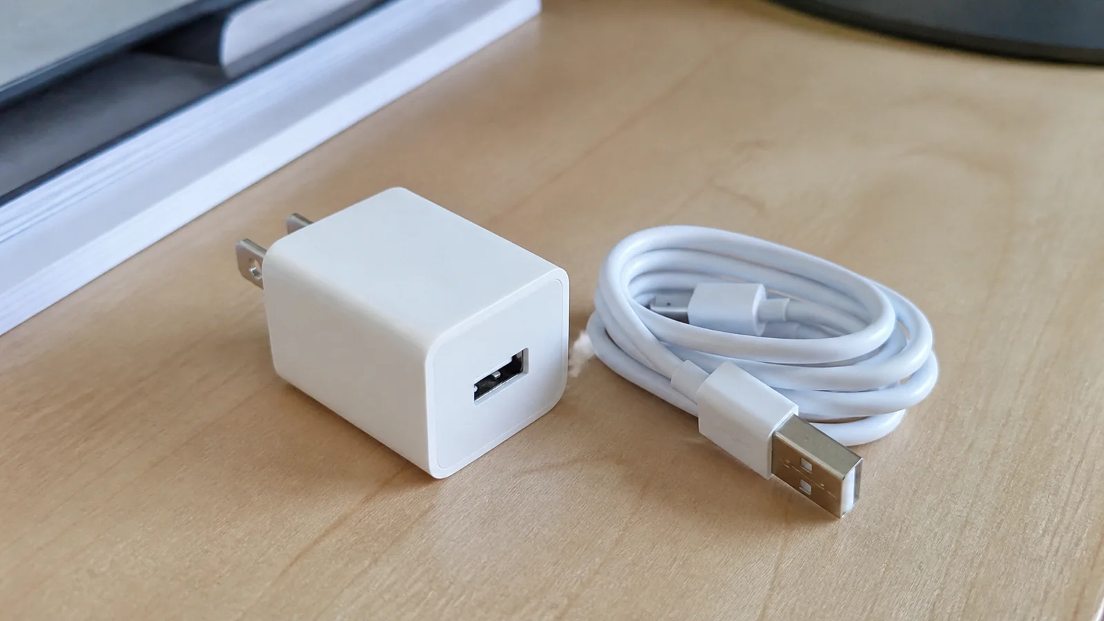 White charging adapter and coiled cable lie on a table.