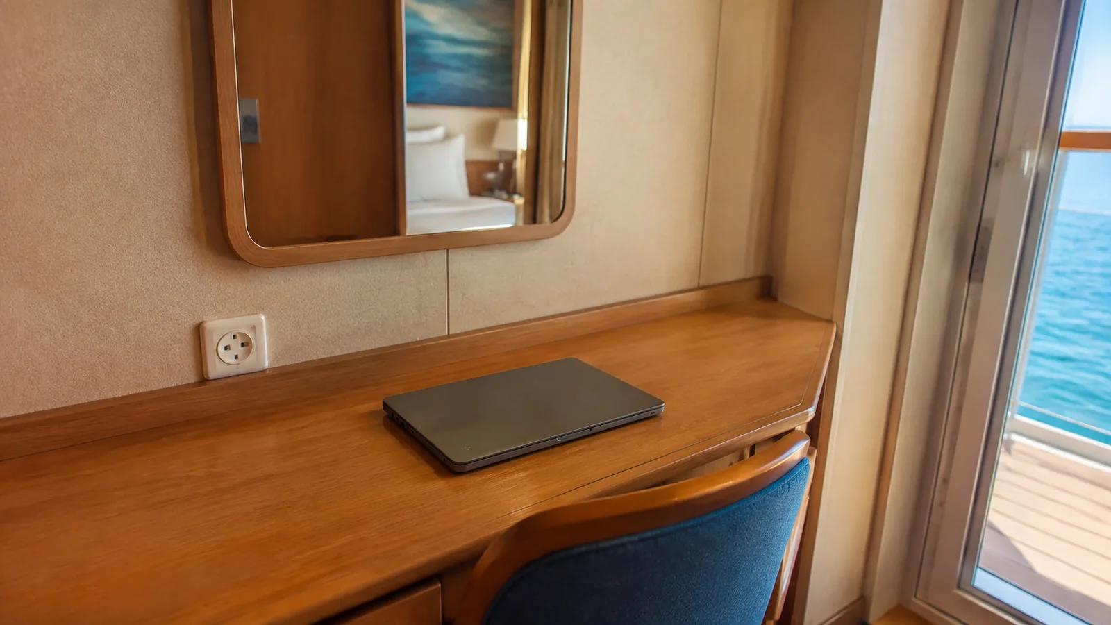 Closed tablet rests on a stateroom desk beneath a mirror.
