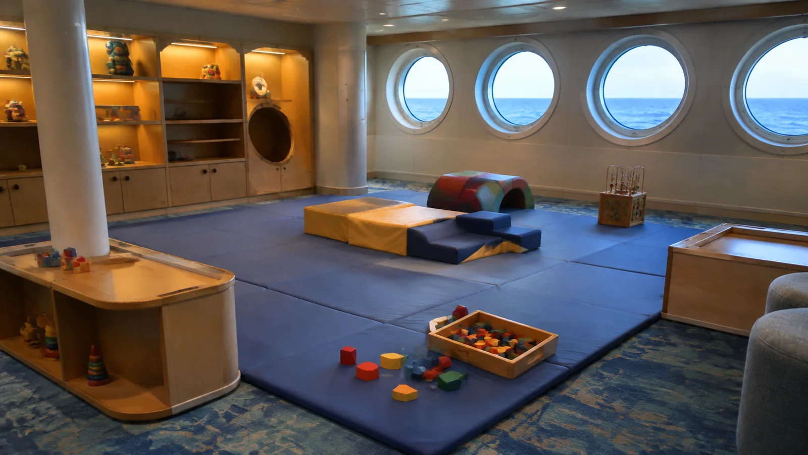 Children's playroom with foam mats, blocks, and round ocean-facing windows.