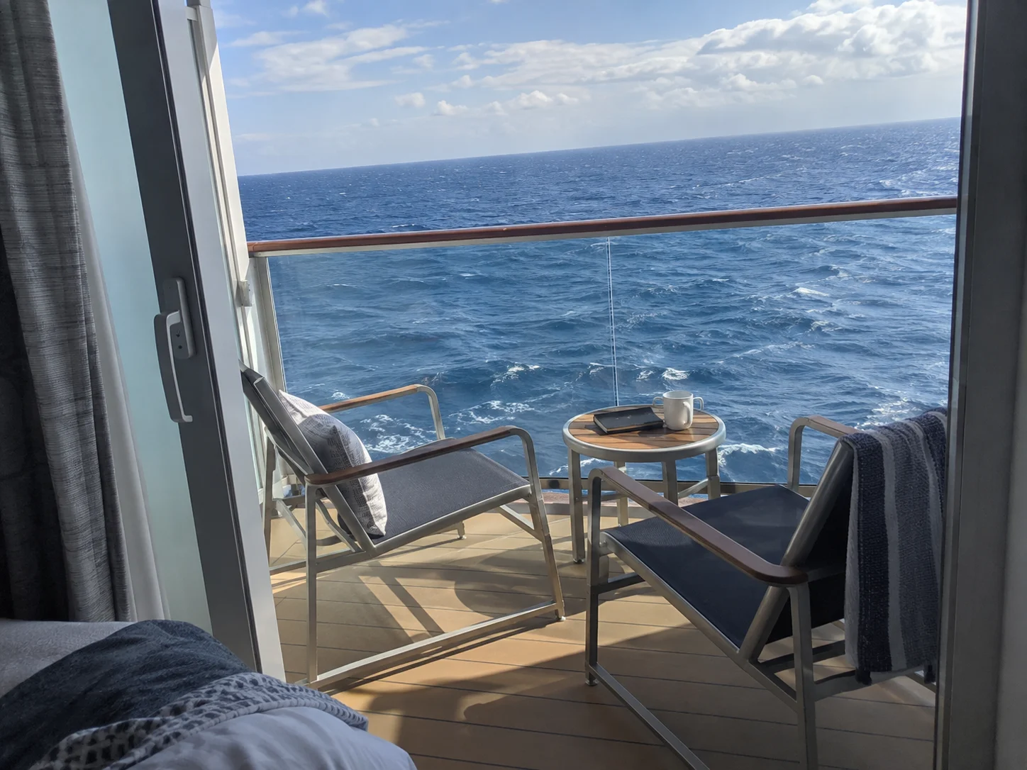 Standard cruise ship balcony with two chairs and an open-ocean view.