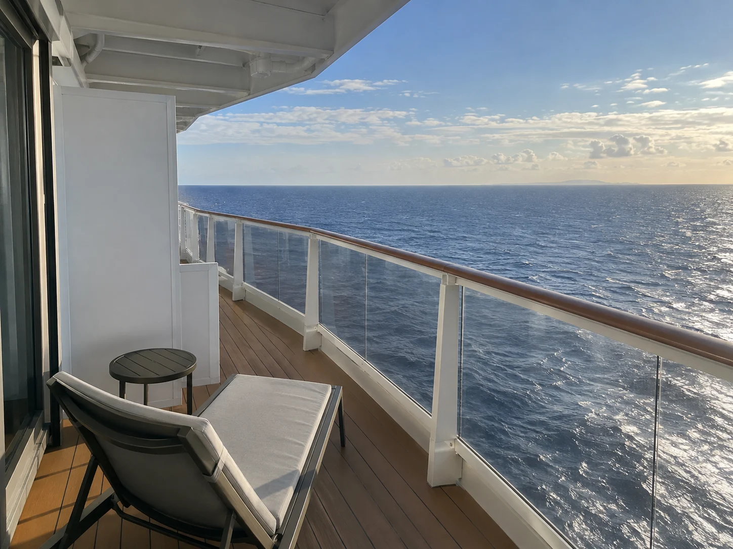 Corner wraparound cruise balcony curving around the ship above the sea.