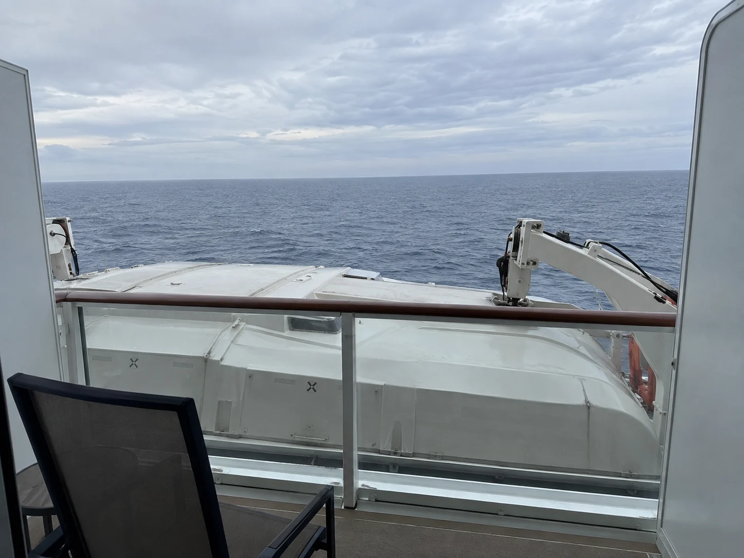 Cruise balcony with a lifeboat blocking much of the lower ocean view.