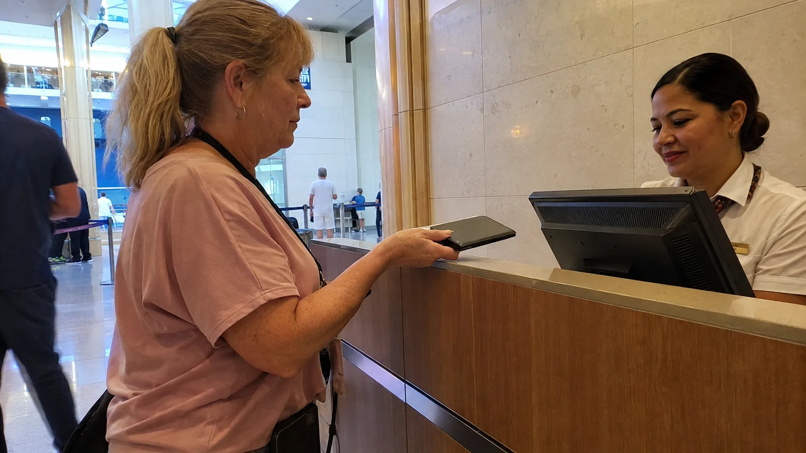 Passenger presents a booklet to a uniformed terminal employee.