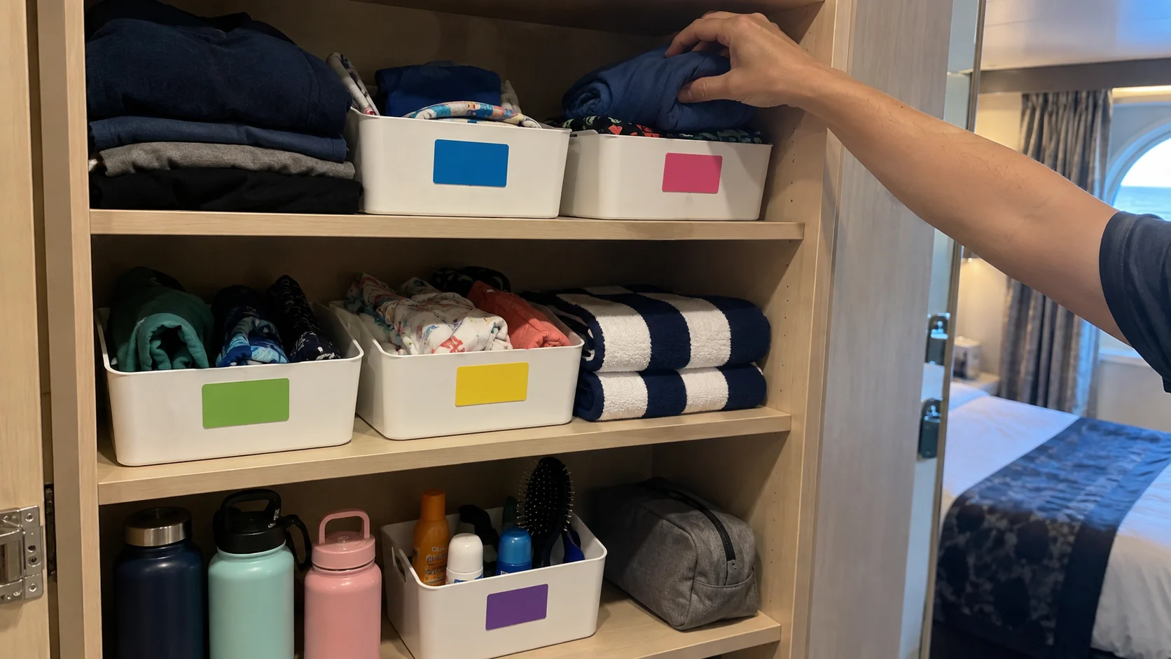 Color-coded removable labels organizing shared cruise cabin storage for a family