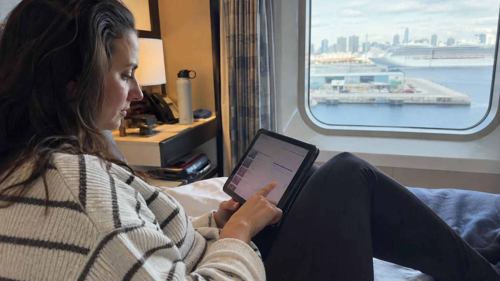 Traveler downloading entertainment on a tablet in a cruise cabin before sail-away