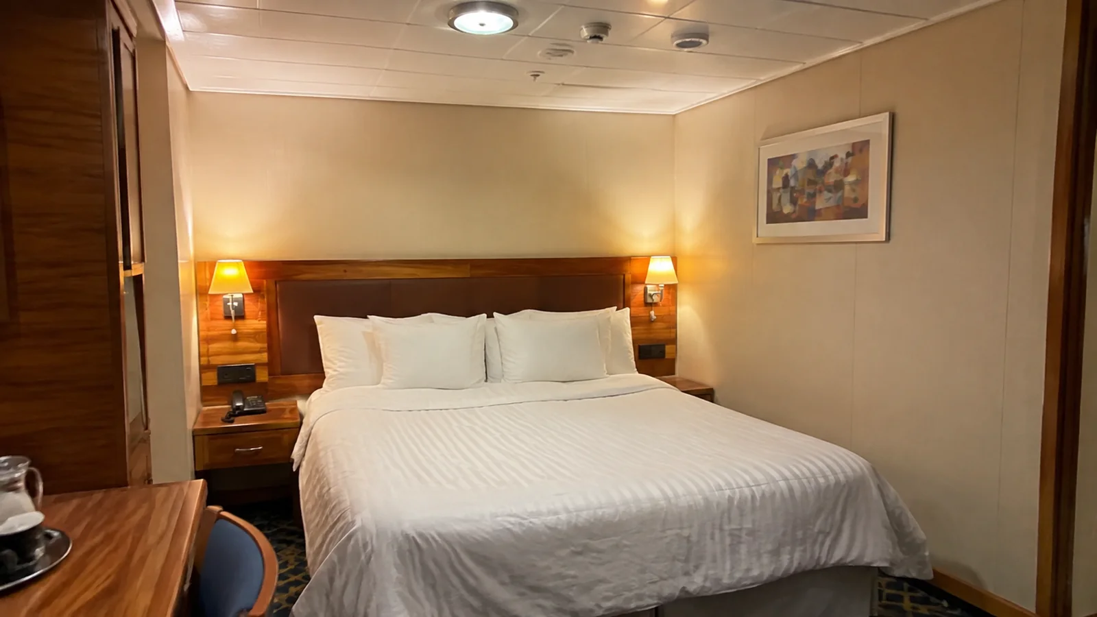 Double bed sits between two bedside lamps in a compact room.