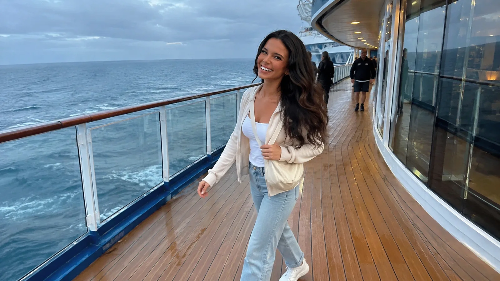 Woman wearing light trousers and an open shirt on a cruise promenade.