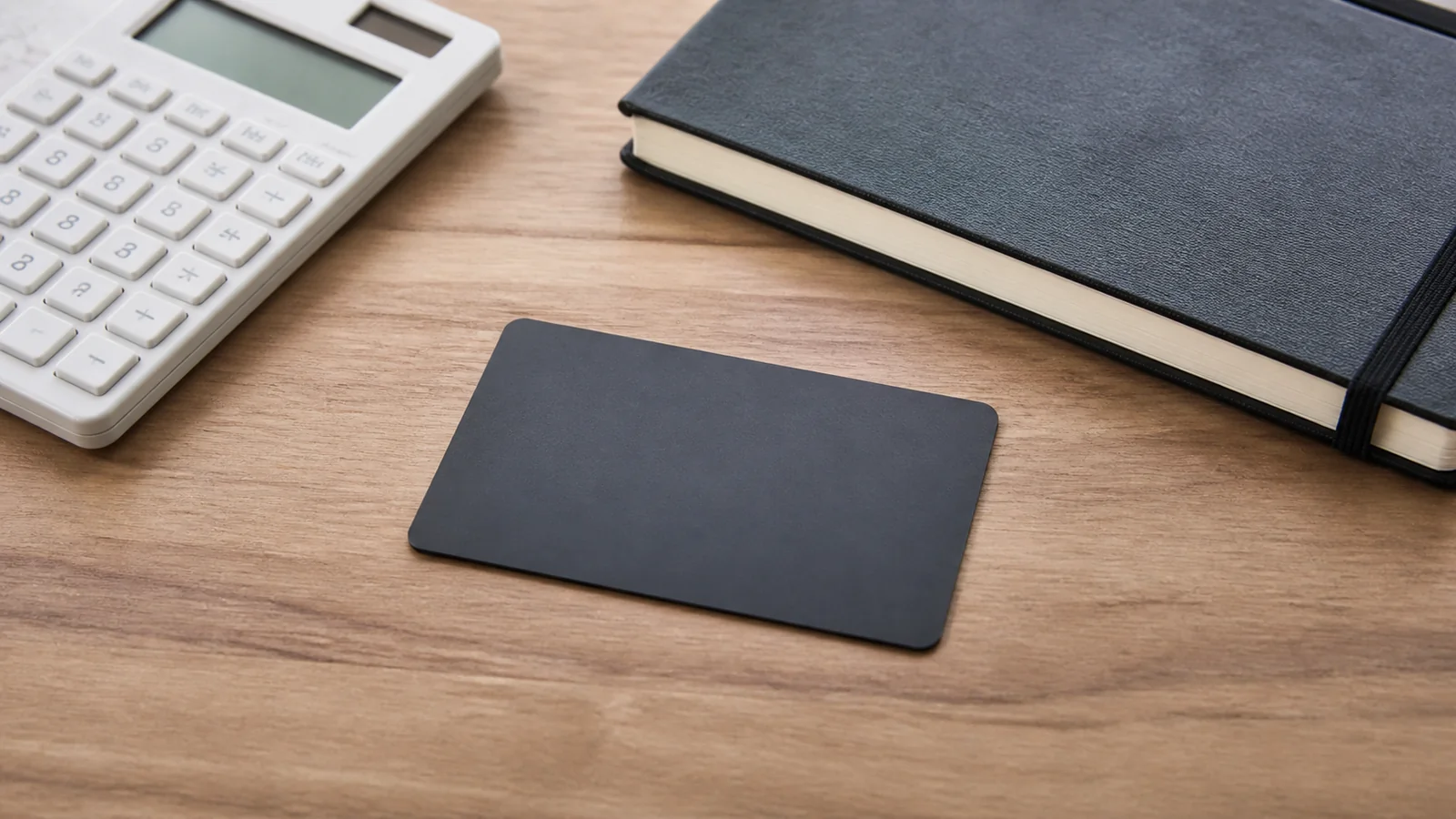 Plain dark card lies beside a calculator and notebook.