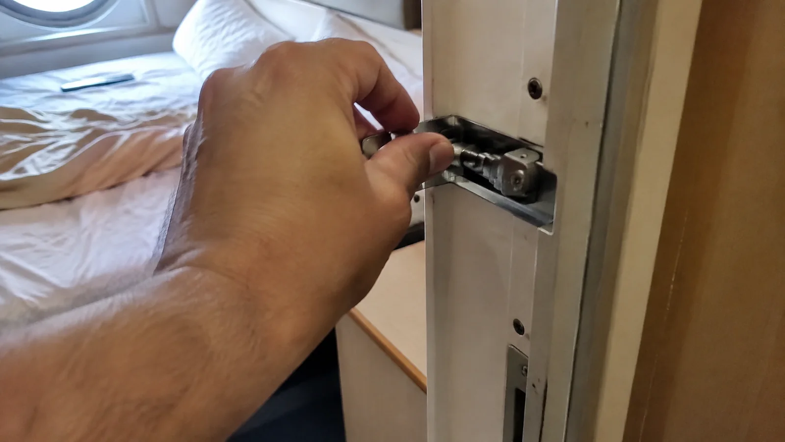 Hand examining a metal latch on an interior cabin door.