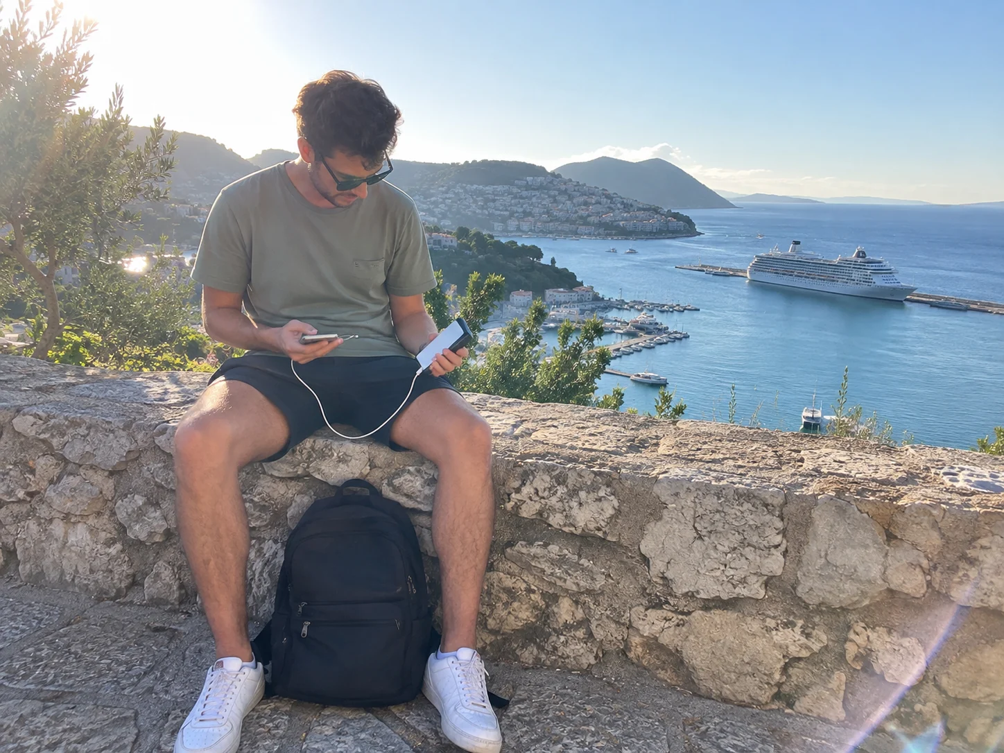 Traveler charging a phone from a compact power bank during a port day