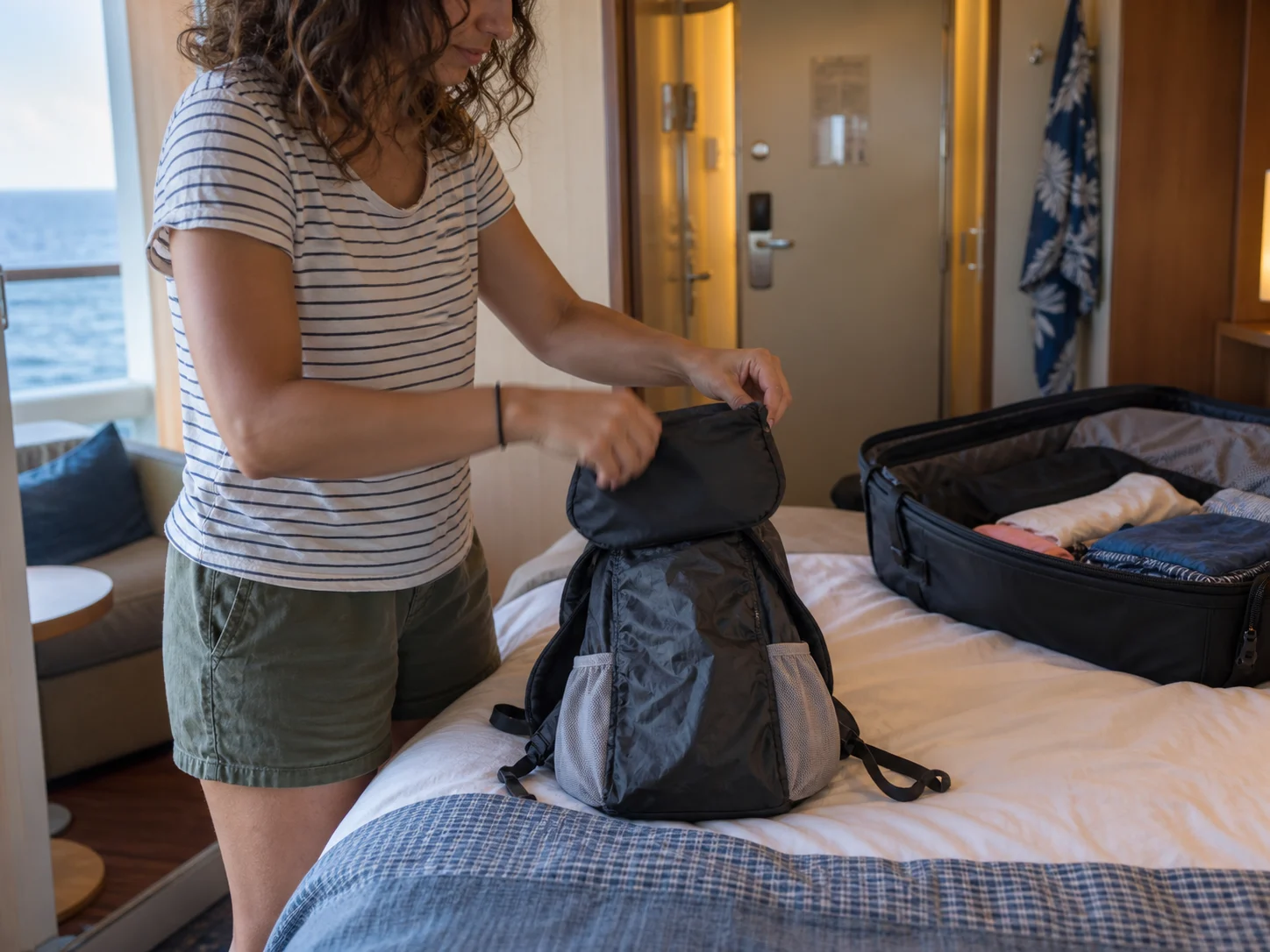 Packable day bag being unfolded on a cruise cabin bed