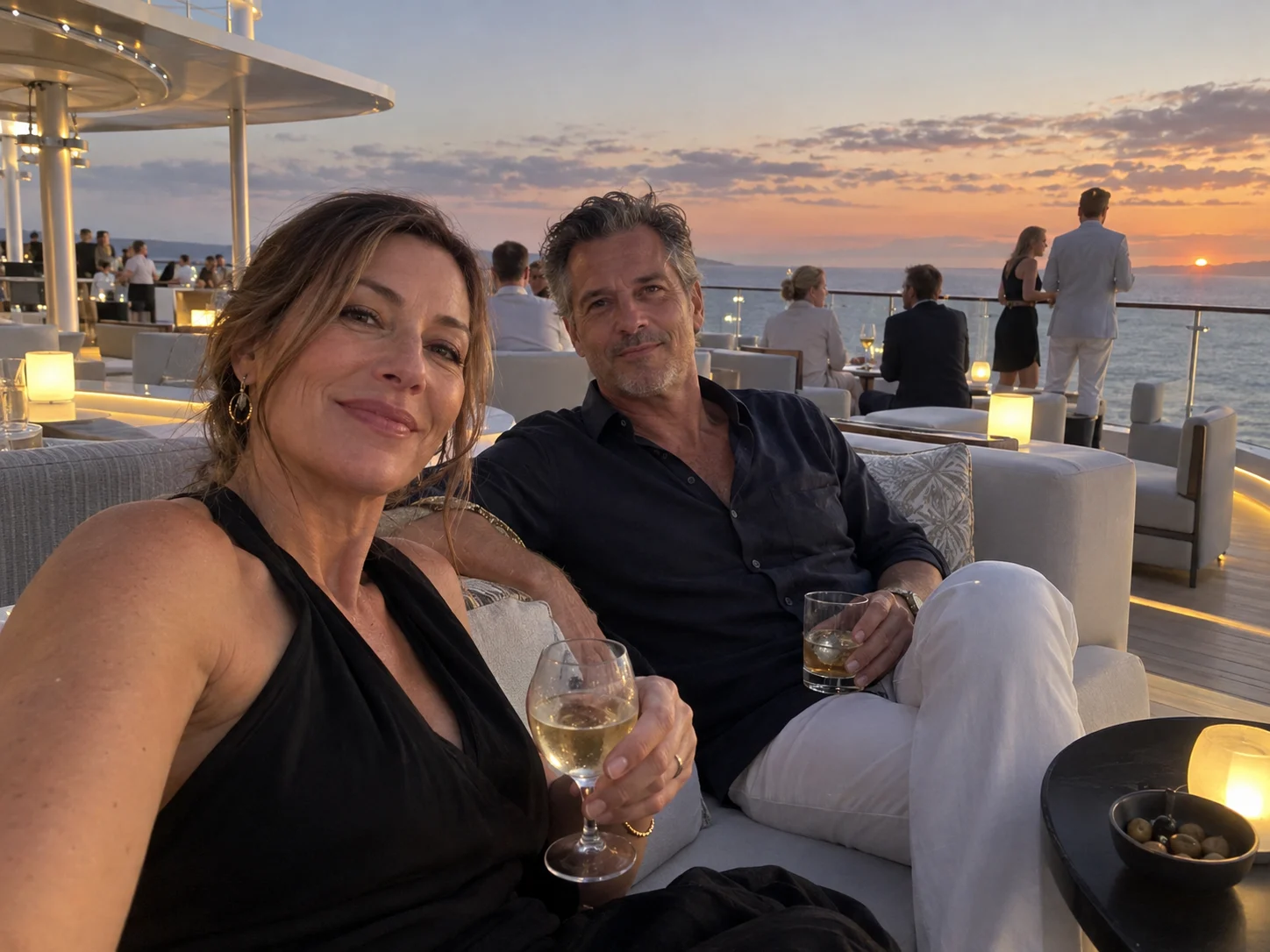 Adult couple relaxing in a sophisticated rooftop cruise lounge at sunset.