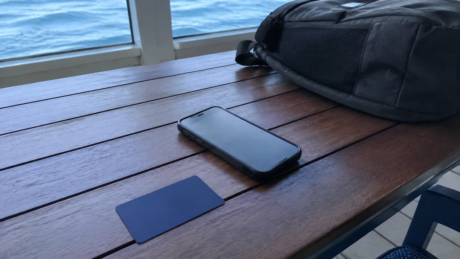 Phone and plain blue card lie beside a black bag.
