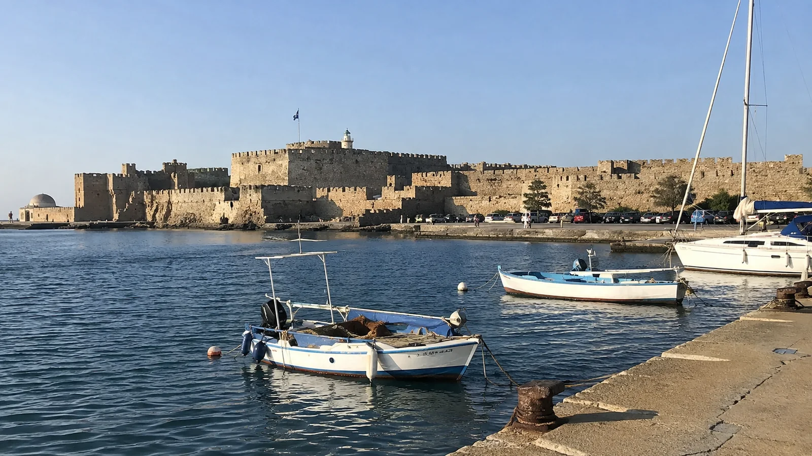 Small boats moored in front of a stone waterfront fortress.