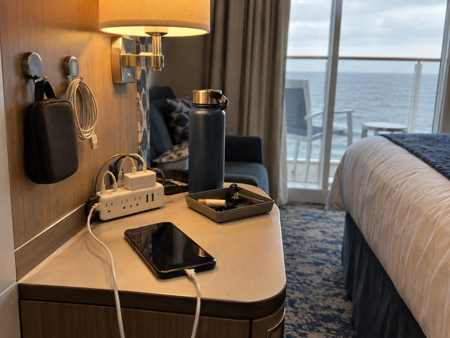 Cruise cabin nightstand organized with chargers, power strip, clips, and cable pouch