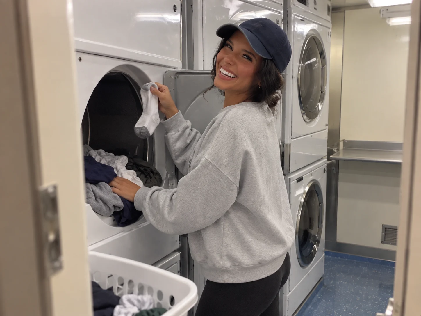 Woman washing a few cruise clothes in a compact self-service laundry room