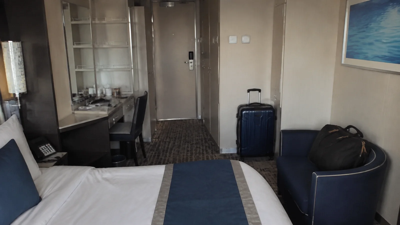 Ship cabin with a suitcase near the door and a bag on a chair.