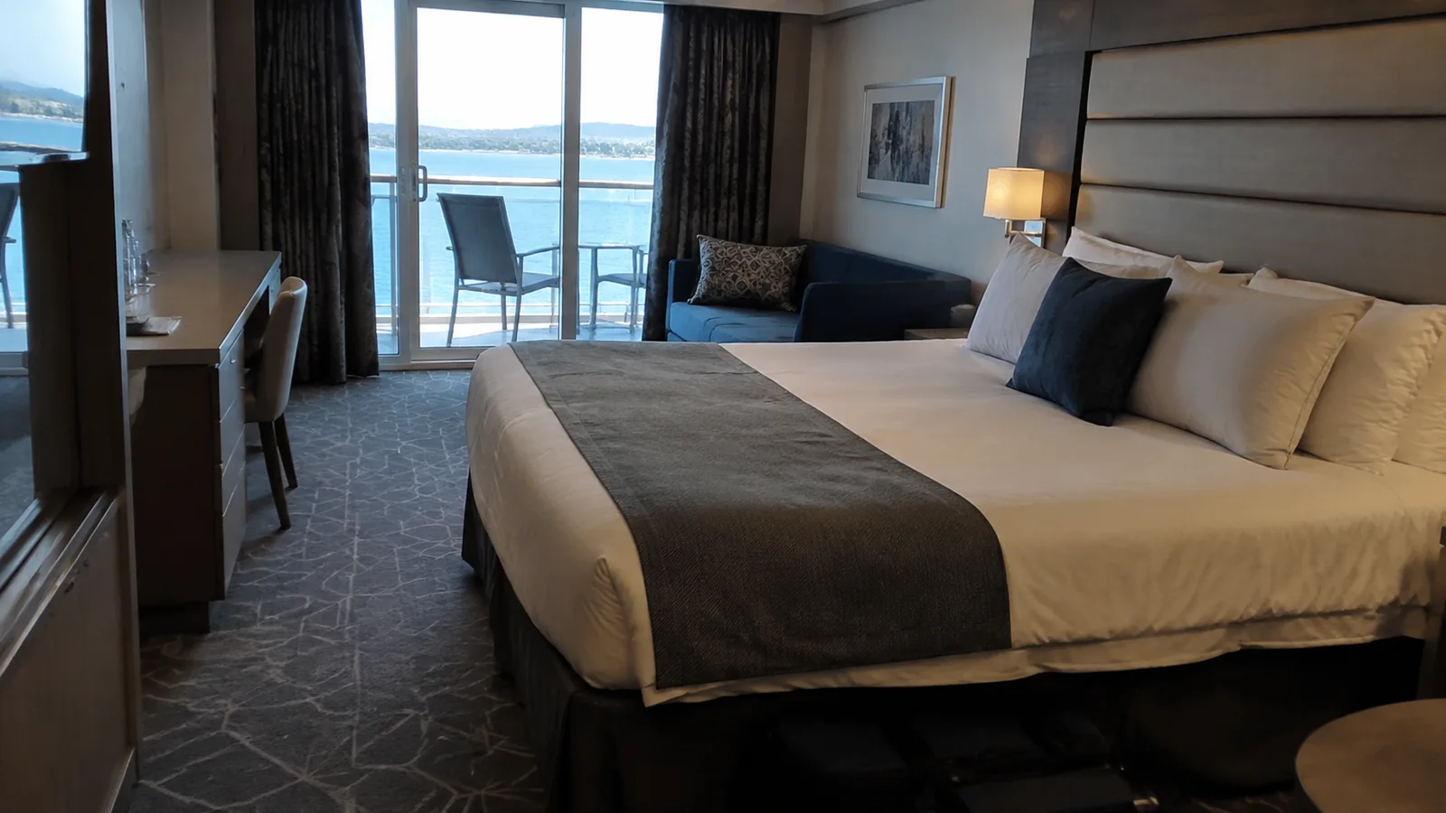 Double bed and desk in a cabin with an ocean-view balcony.