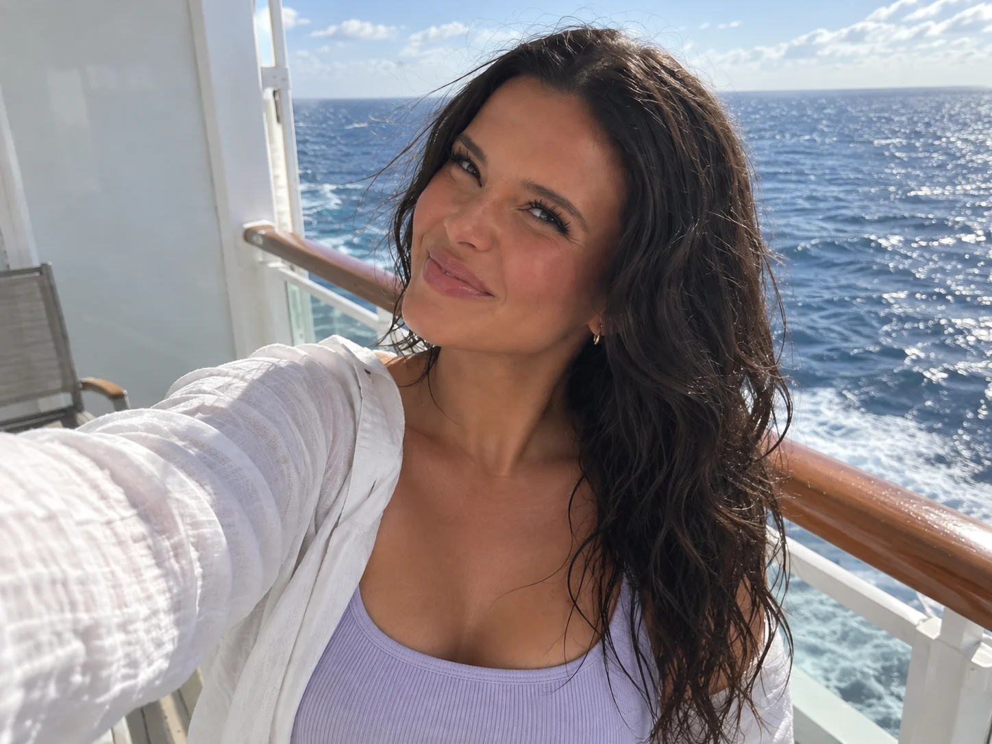 Ellie looks over her shoulder toward the camera beside the open sea.
