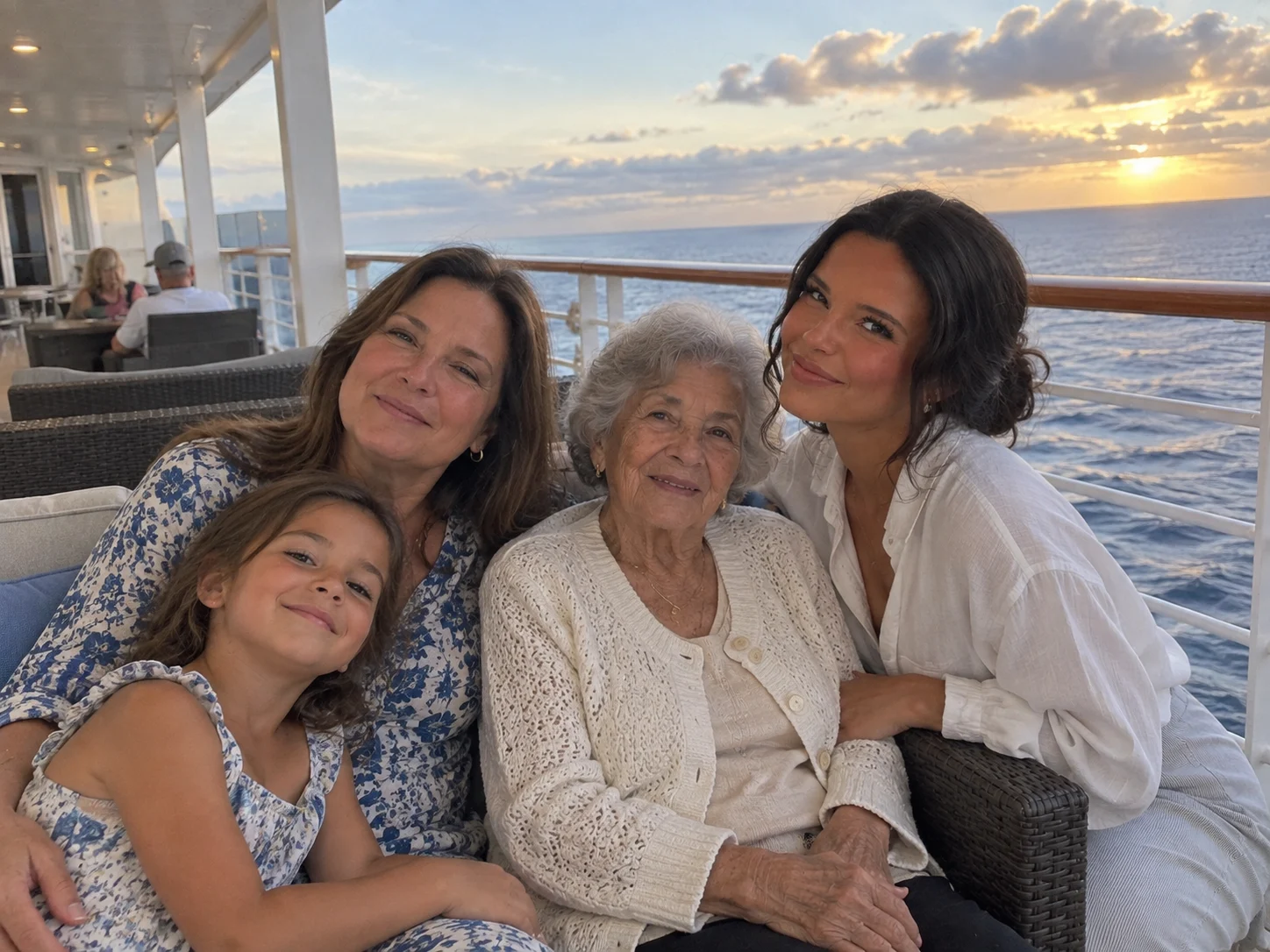 Ellie poses with three generations of family against a calm ocean backdrop.