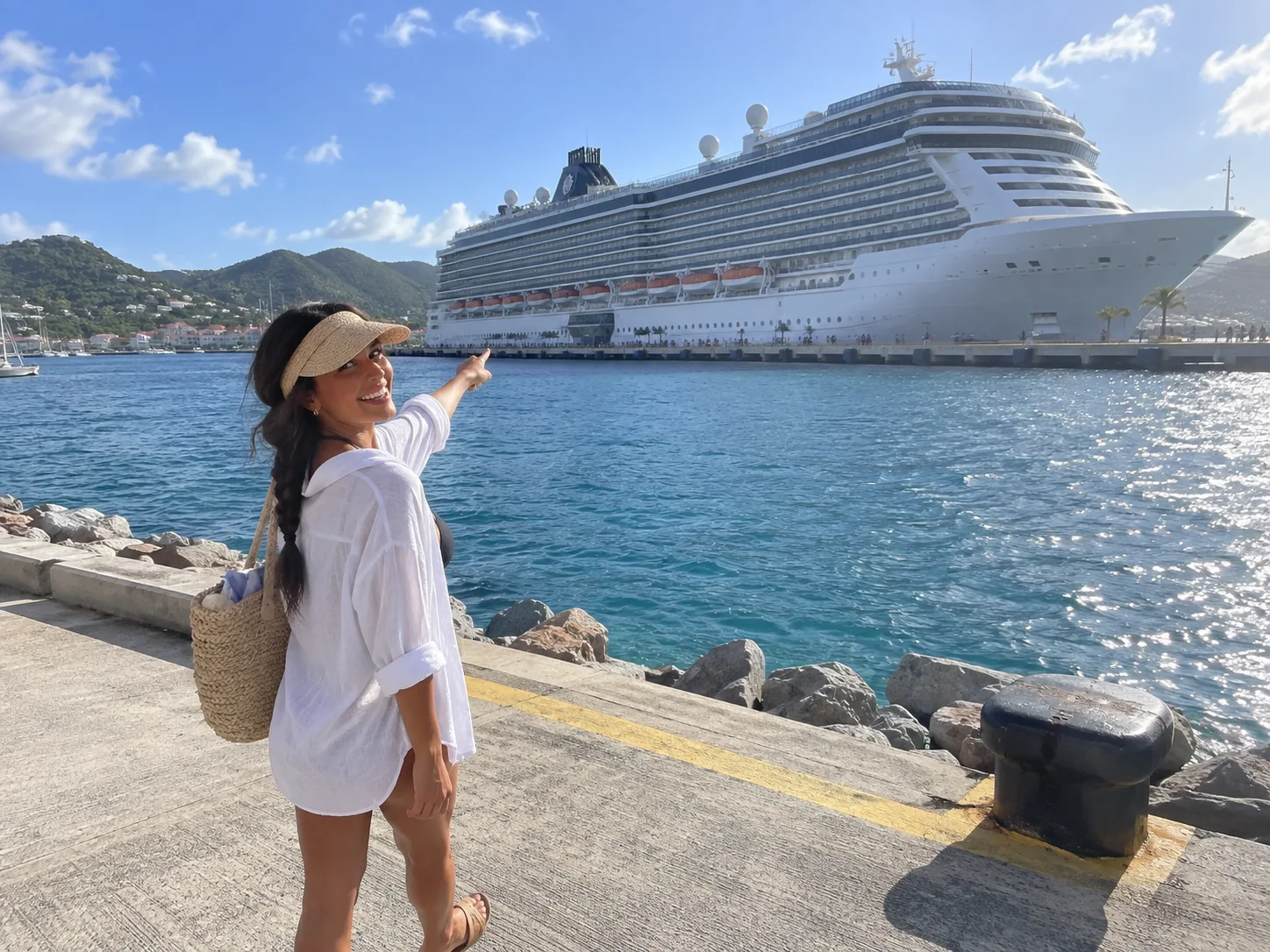 Ellie stands on shore with her cruise ship visible across the harbor.