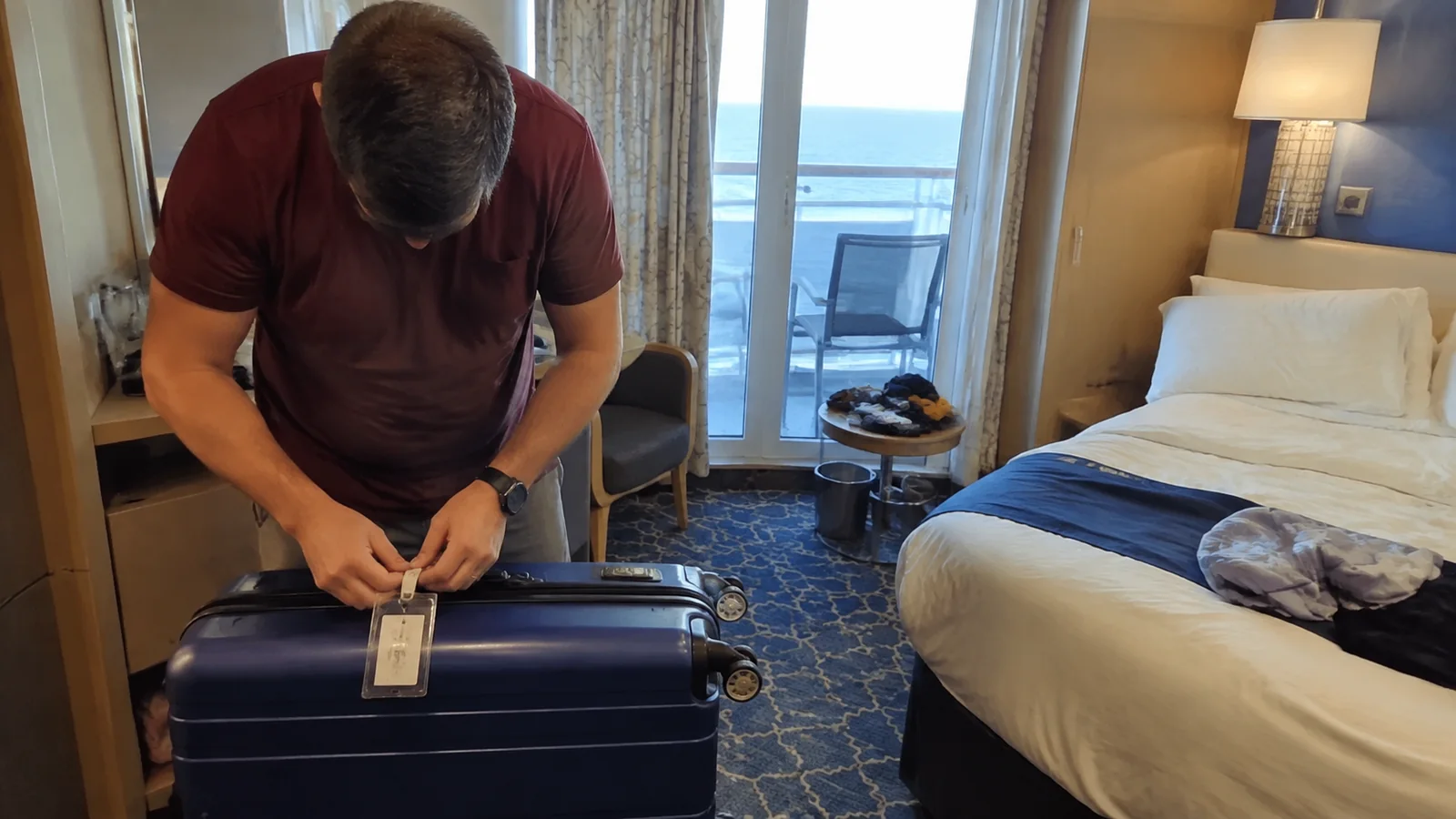 Traveler attaches a luggage tag to a suitcase inside a cabin.