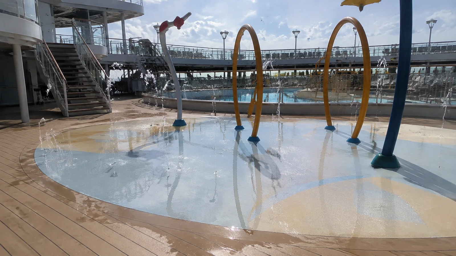 Empty splash pad with water jets and curved spray features on a ship deck.