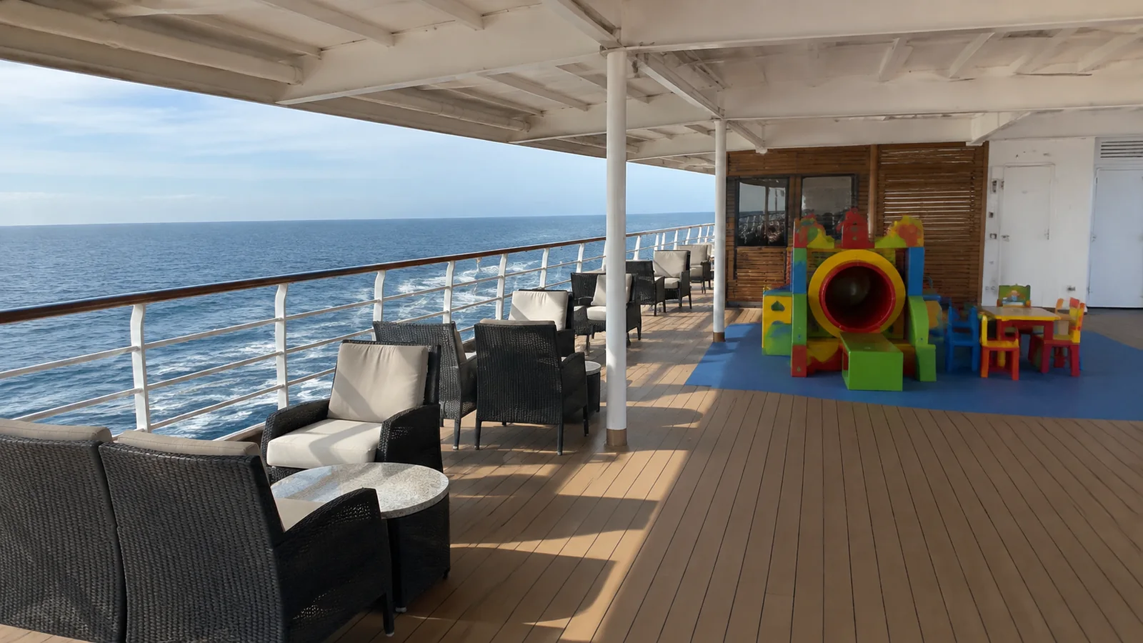 Covered ship deck with lounge chairs and colorful children's play equipment.