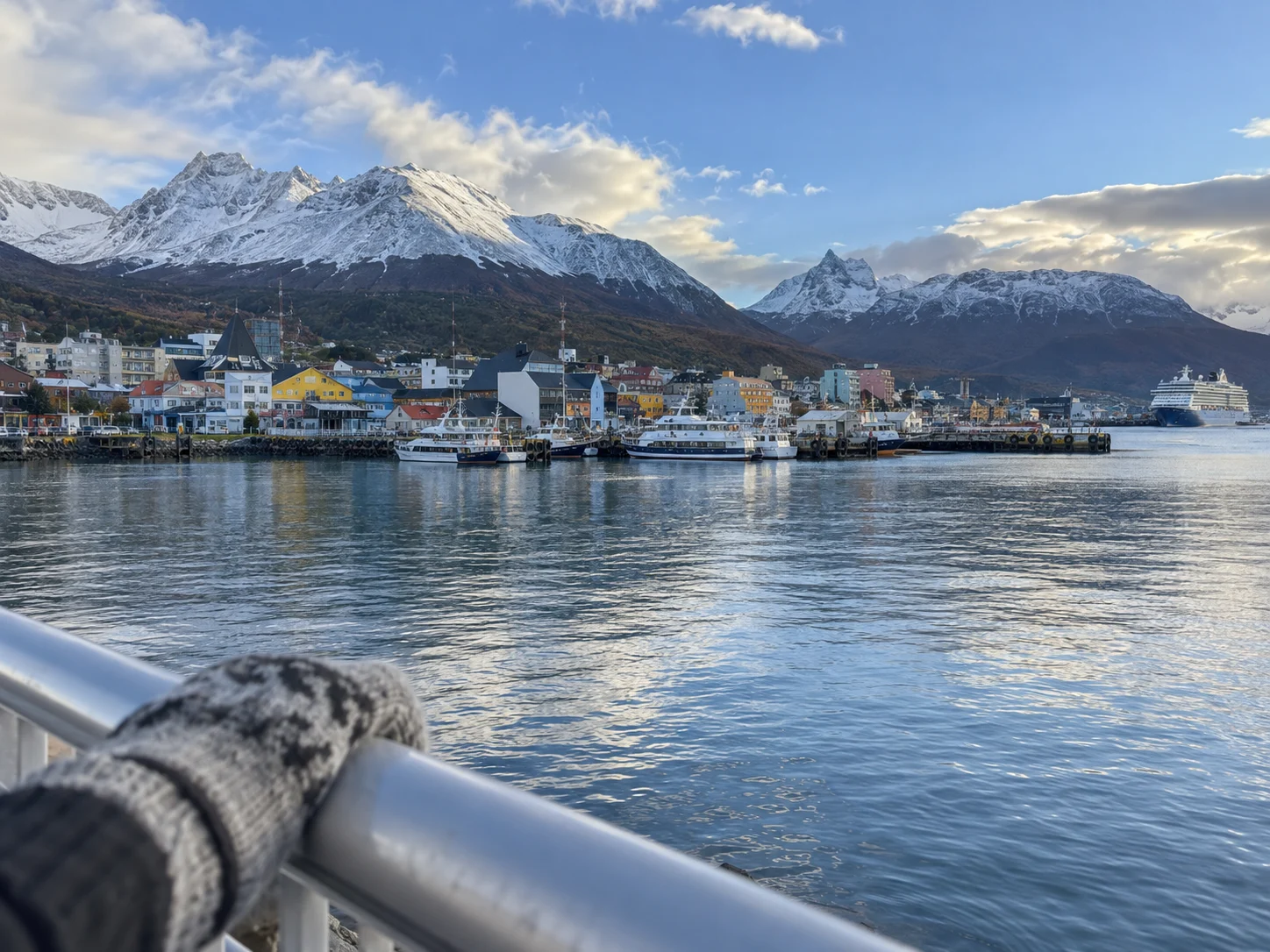 Ushuaia's harbor and colorful buildings stand beneath snow-dusted mountains.