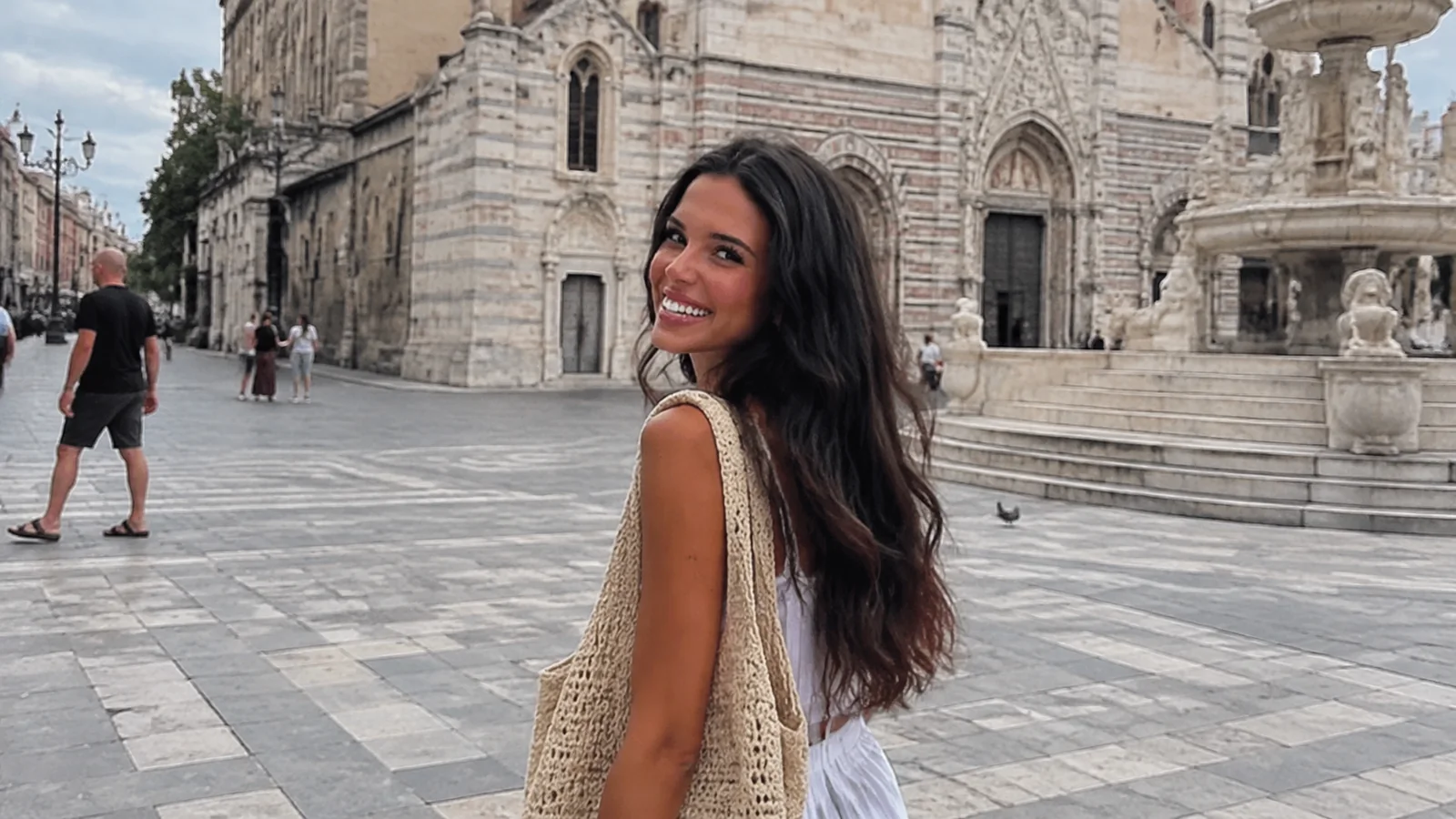 Smiling woman standing in a square beside an ornate stone cathedral