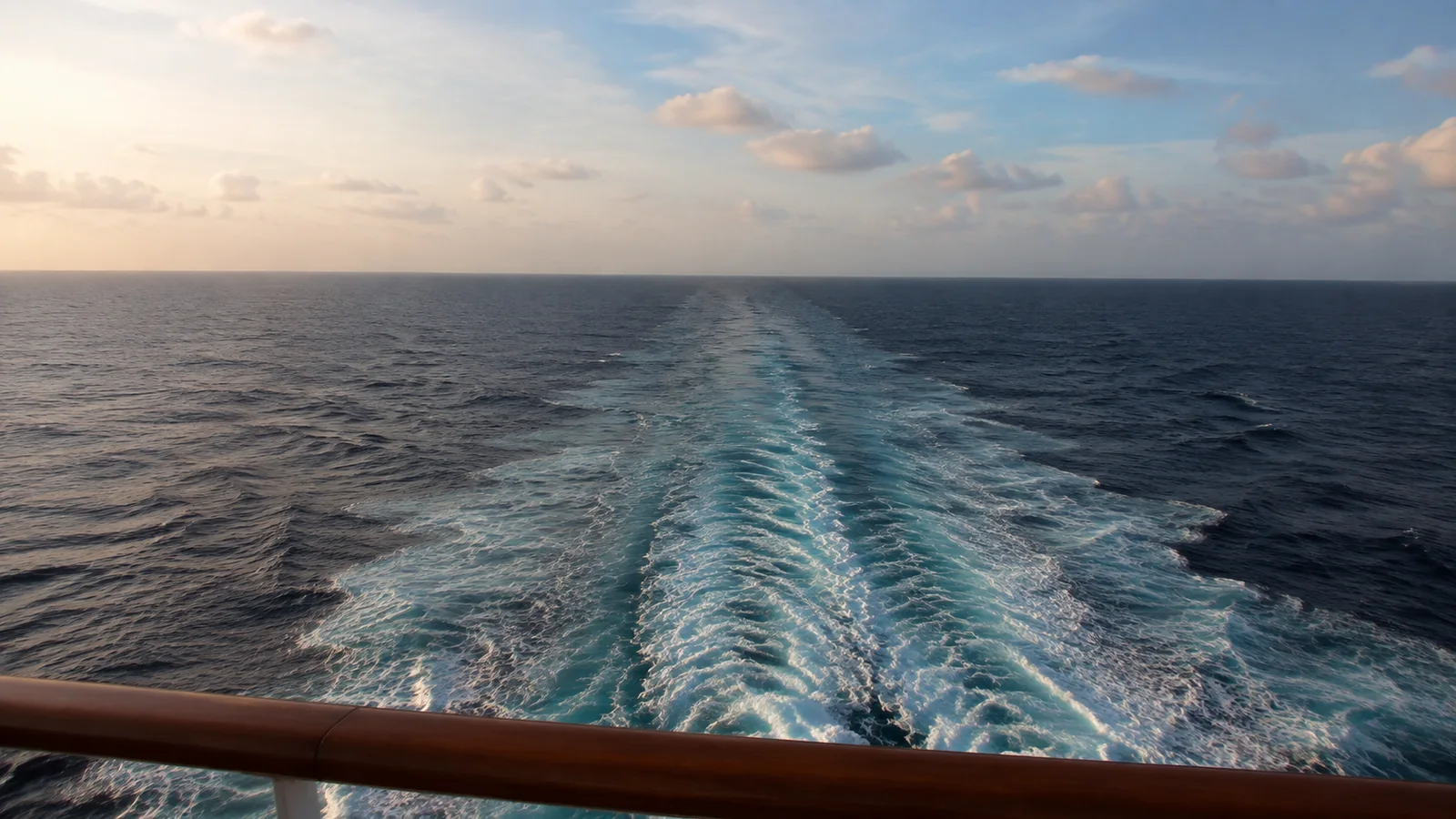 Ship's wake stretching toward the horizon at sunset.