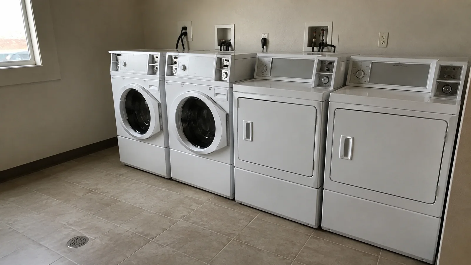 Washers and dryers line a clean room with pale flooring.