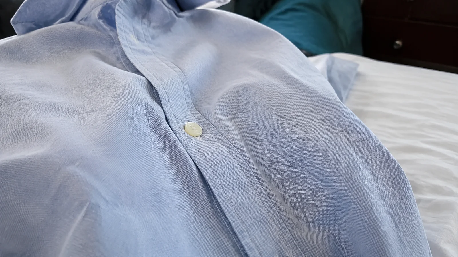 Close-up of buttons and fabric on a light-blue collared shirt.