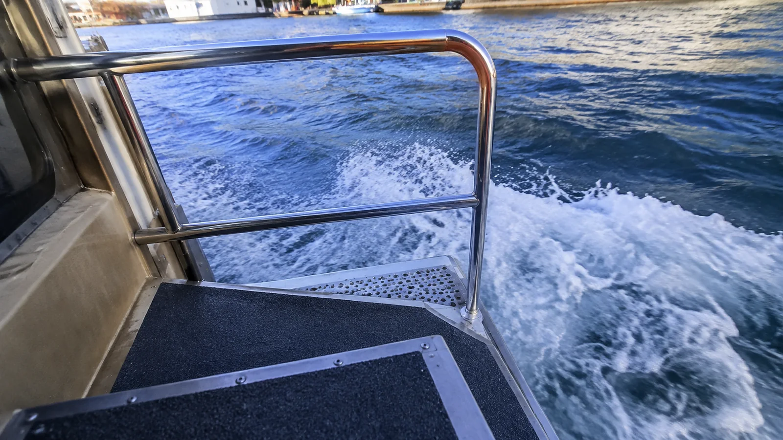 Metal boarding steps and handrail beside moving seawater.