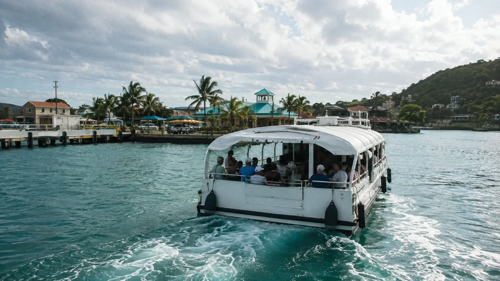 Passenger tender leaving a wake as it approaches a tropical harbor.