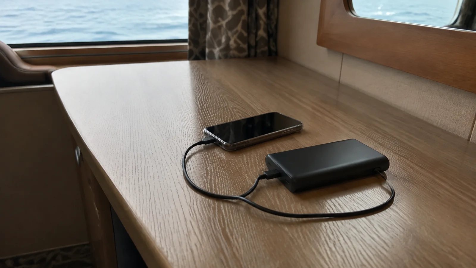 Phone connects to a portable power bank on a wooden surface.