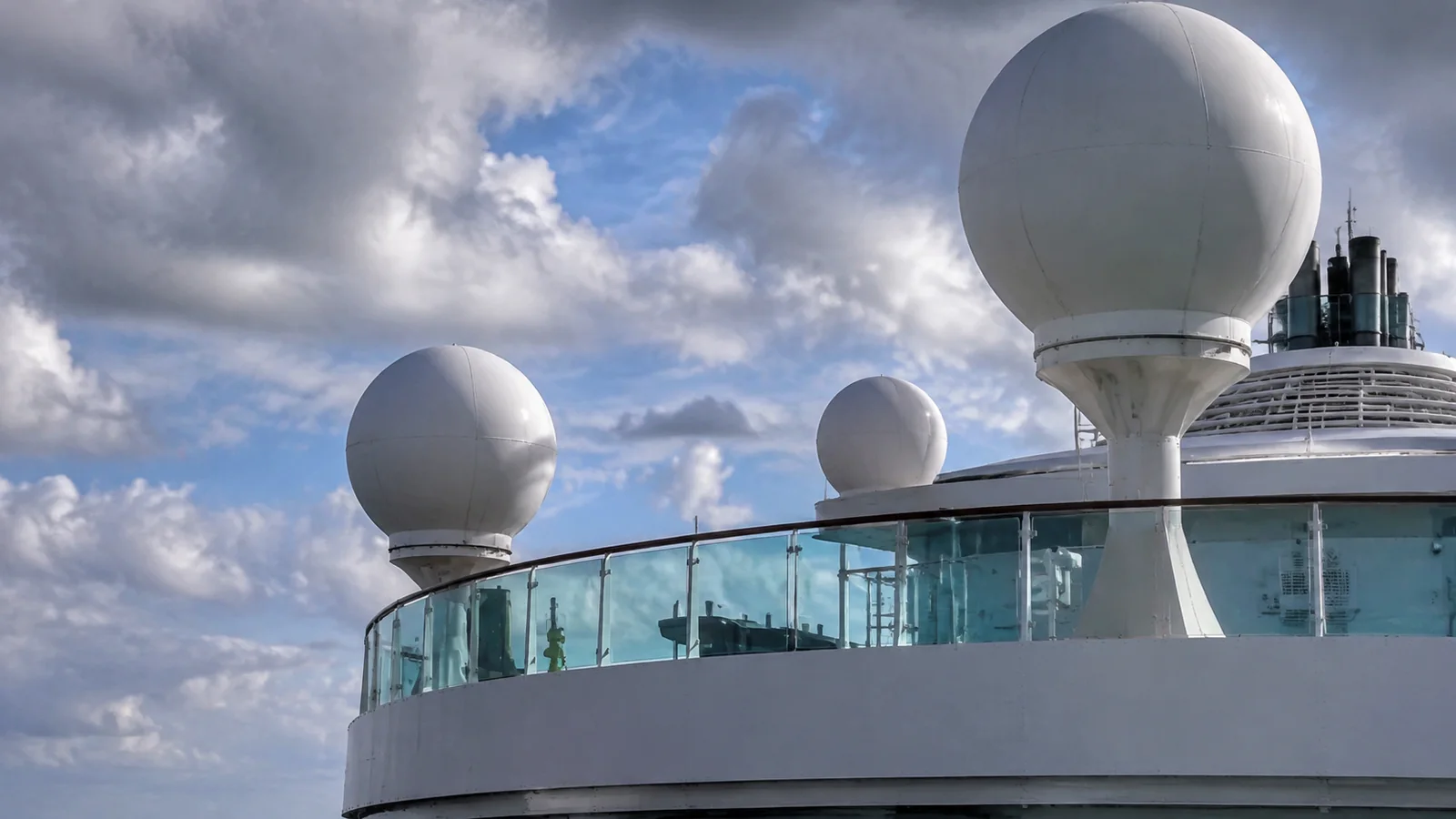White spherical antenna domes rise above a cruise ship deck.