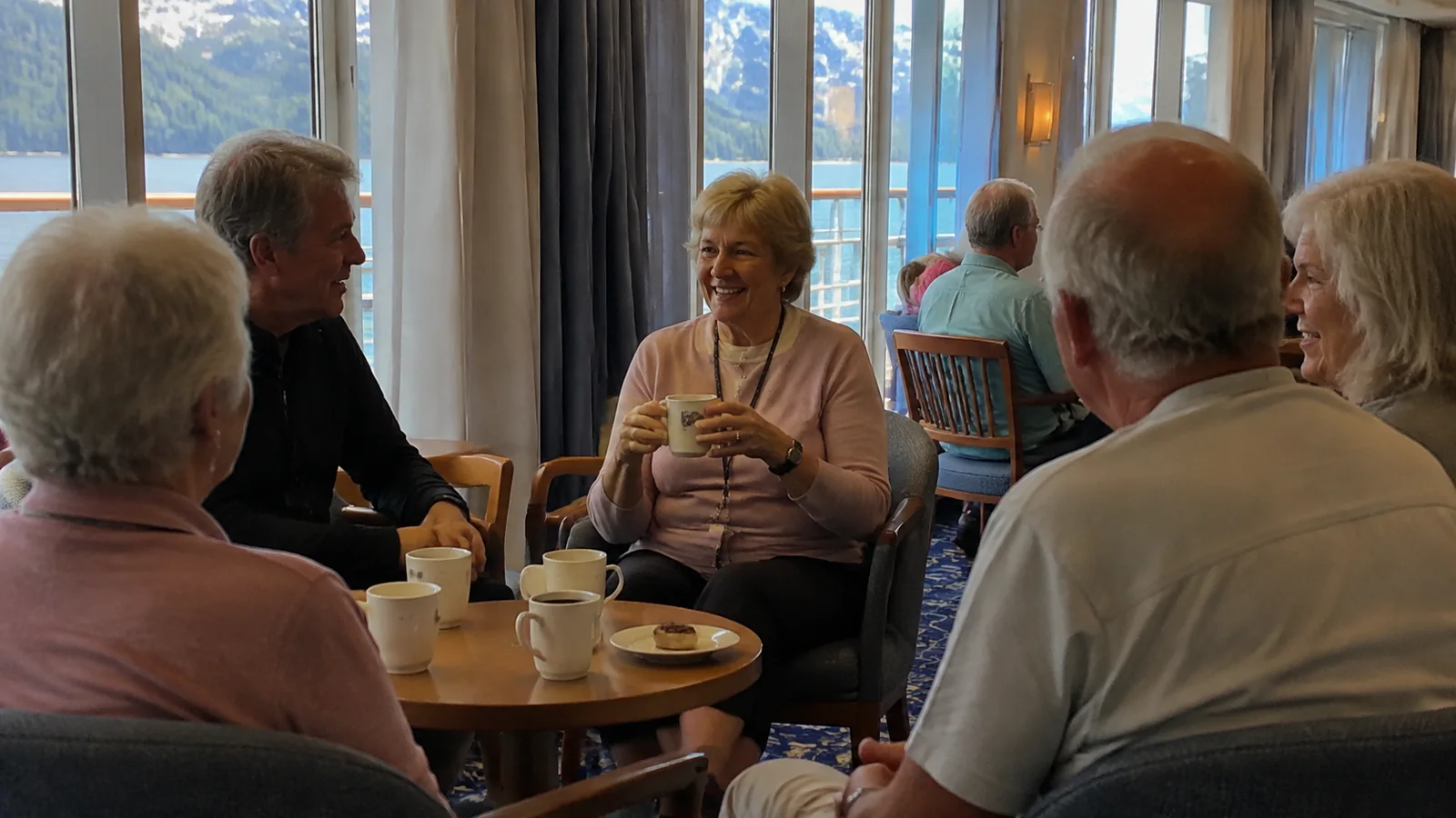 Group of older travelers sharing coffee and conversation around a table.