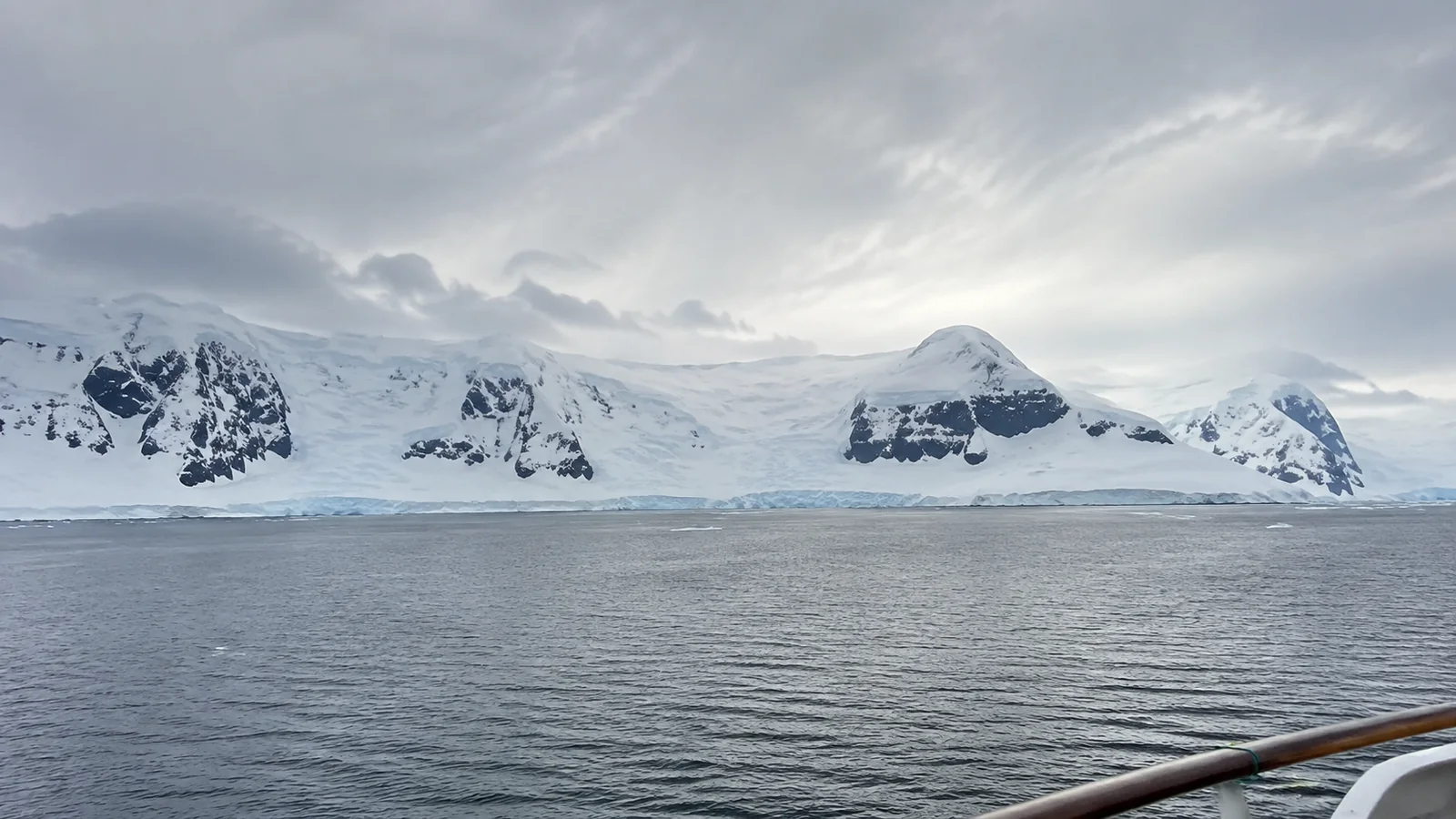 Snow-covered polar coastline beneath an overcast sky.