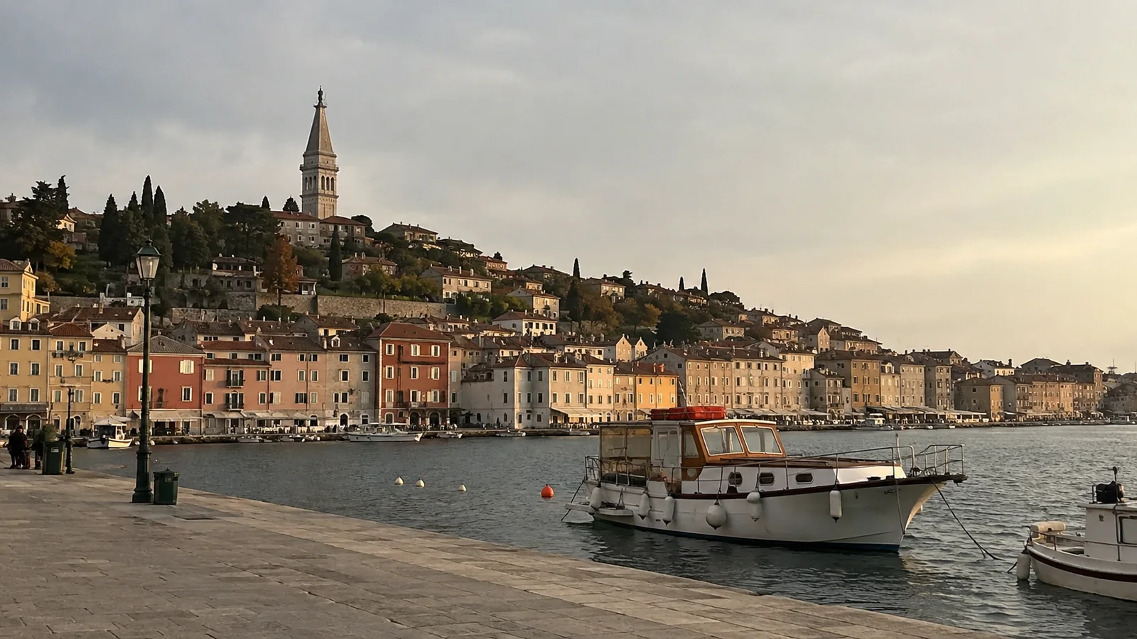 Fishing boat in front of a pastel waterfront town and church tower.