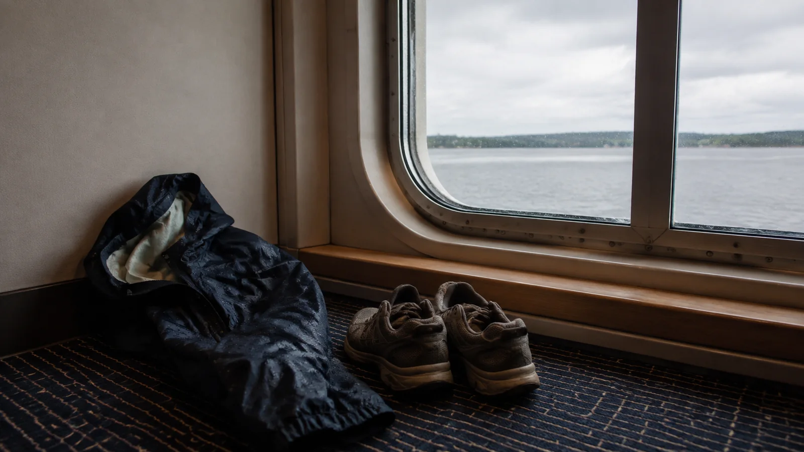 Hiking shoes and a jacket drying beneath a cabin window.