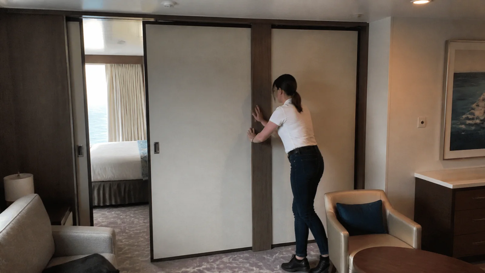 Passenger sliding a partition between the bedroom and sitting area of a suite.