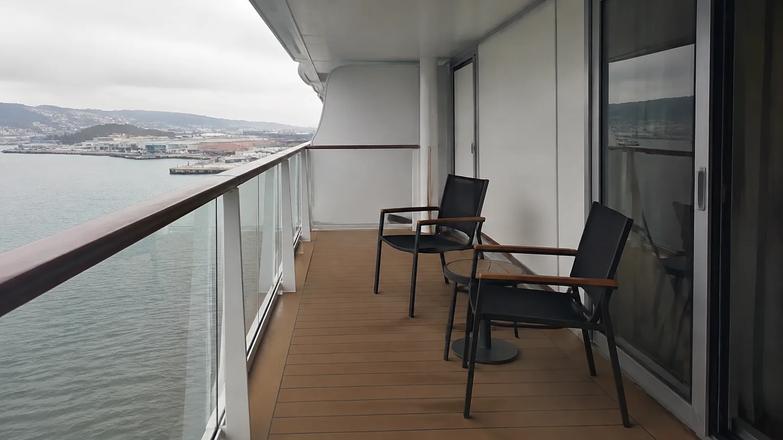 Long private balcony with chairs and a small table.